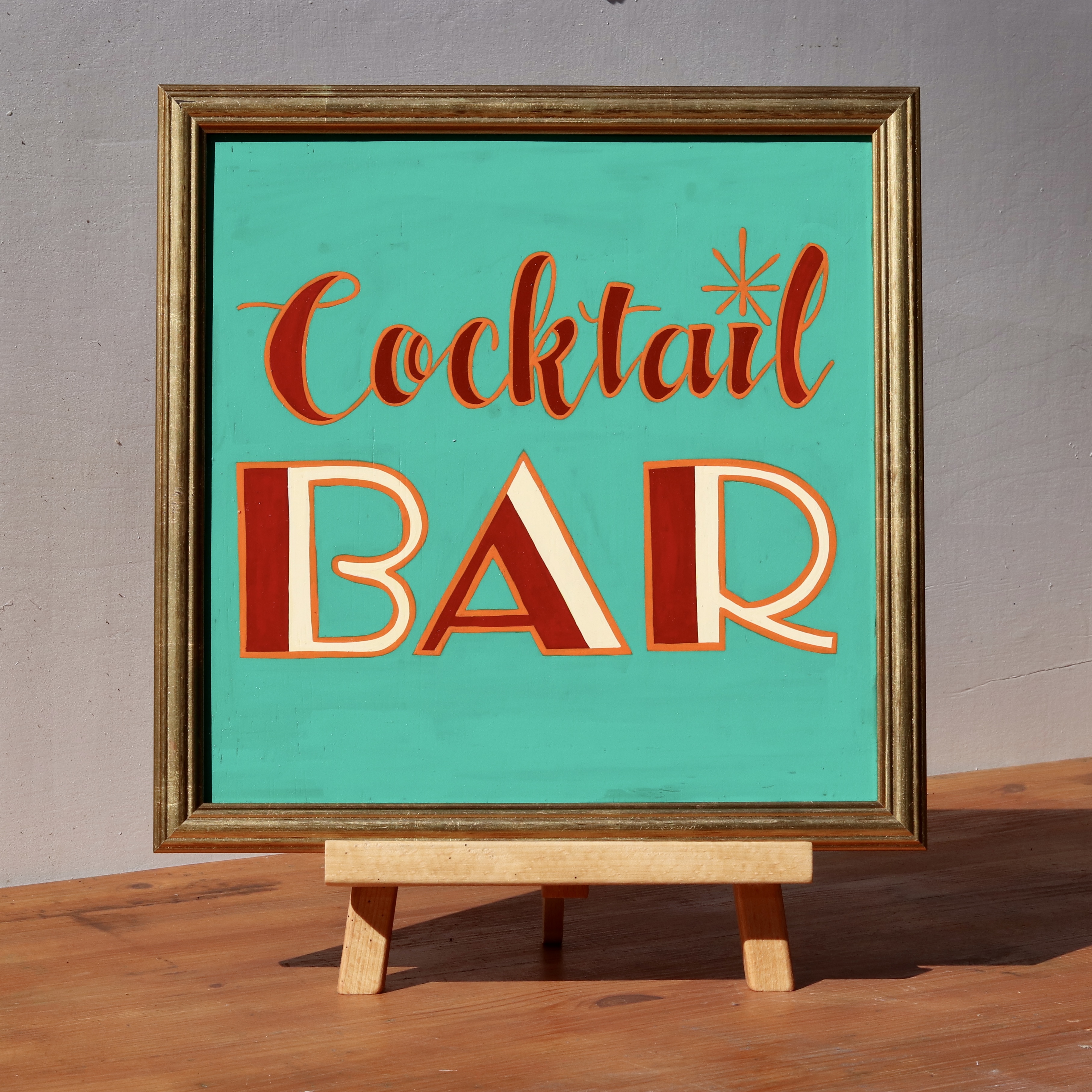 'Cocktail Bar' framed wooden hand-painted word art sign script and art deco style hand lettering in maroon, cream and orange on an emerald green background