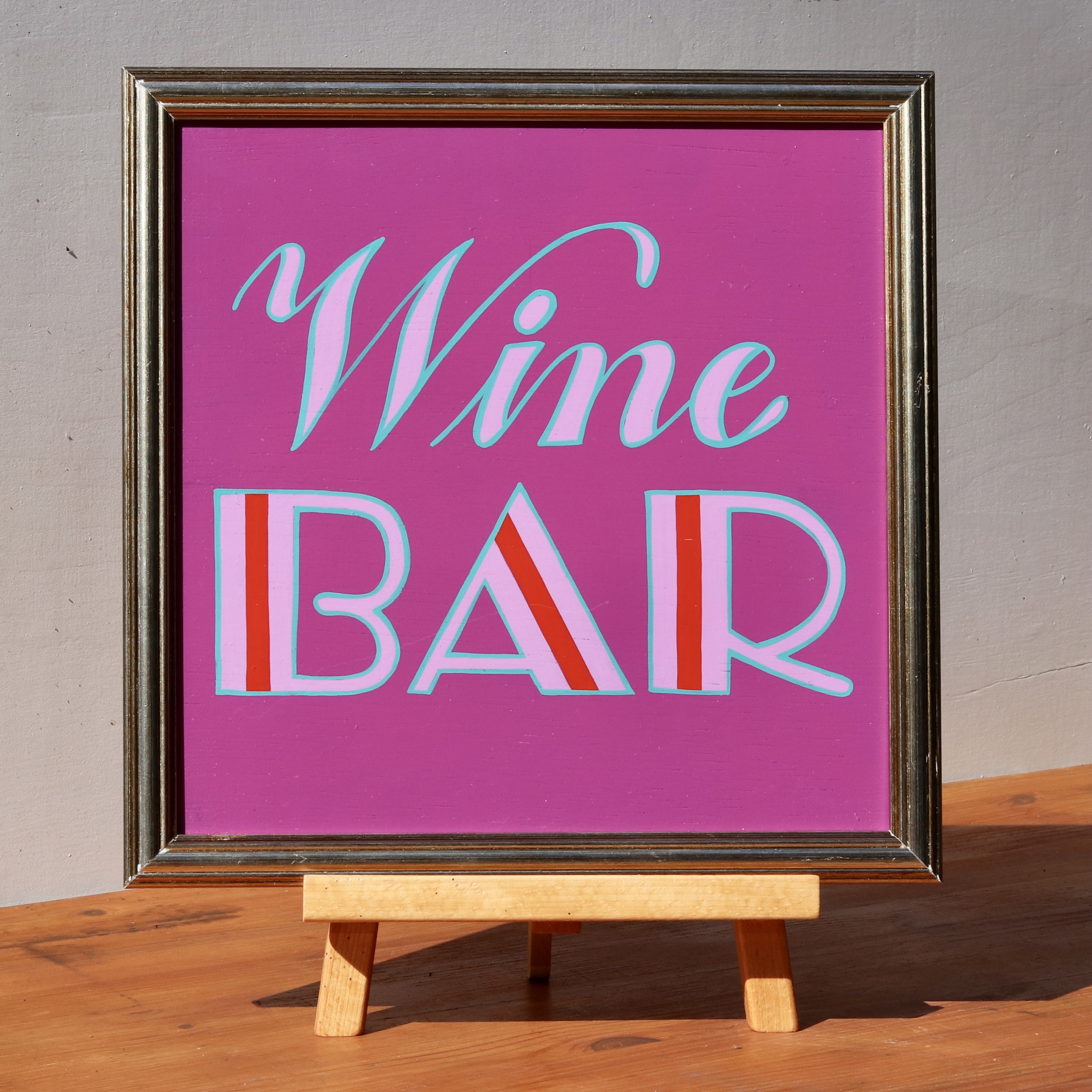 'Wine Bar' framed wooden hand-painted word art sign script and art deco style hand lettering in lilac and magenta on a purple background