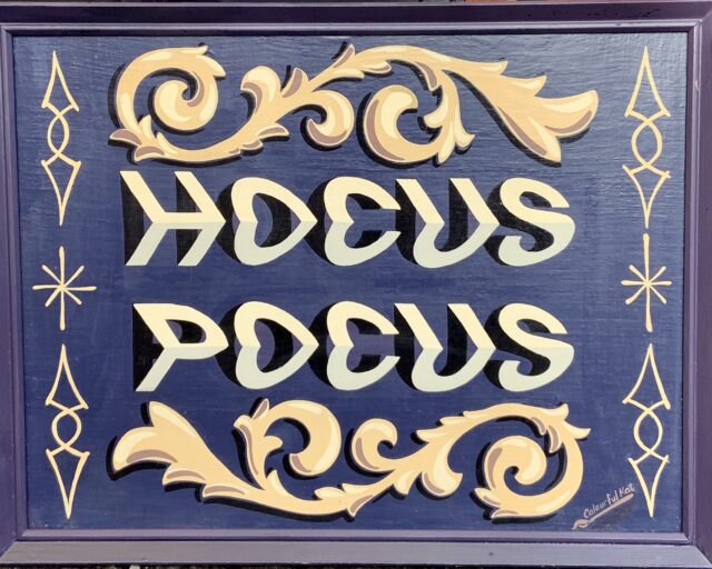 Hocus Pocus optical illusion lettering and gypsy scrolls in cream & beige on purple background