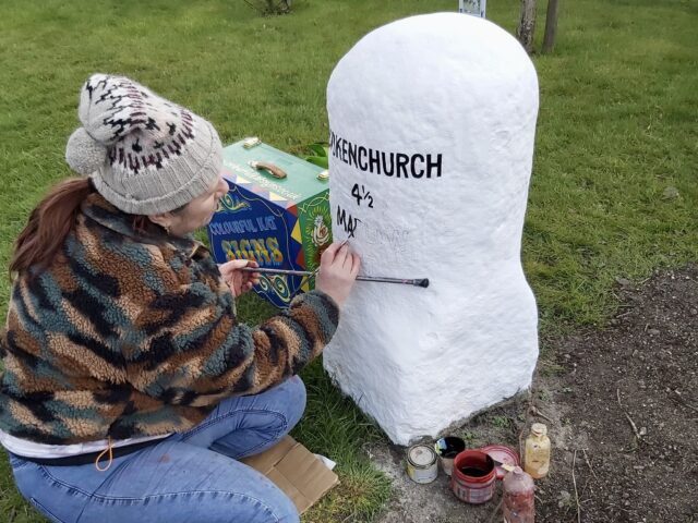 Me painting the black lettering onto a white painted milestone