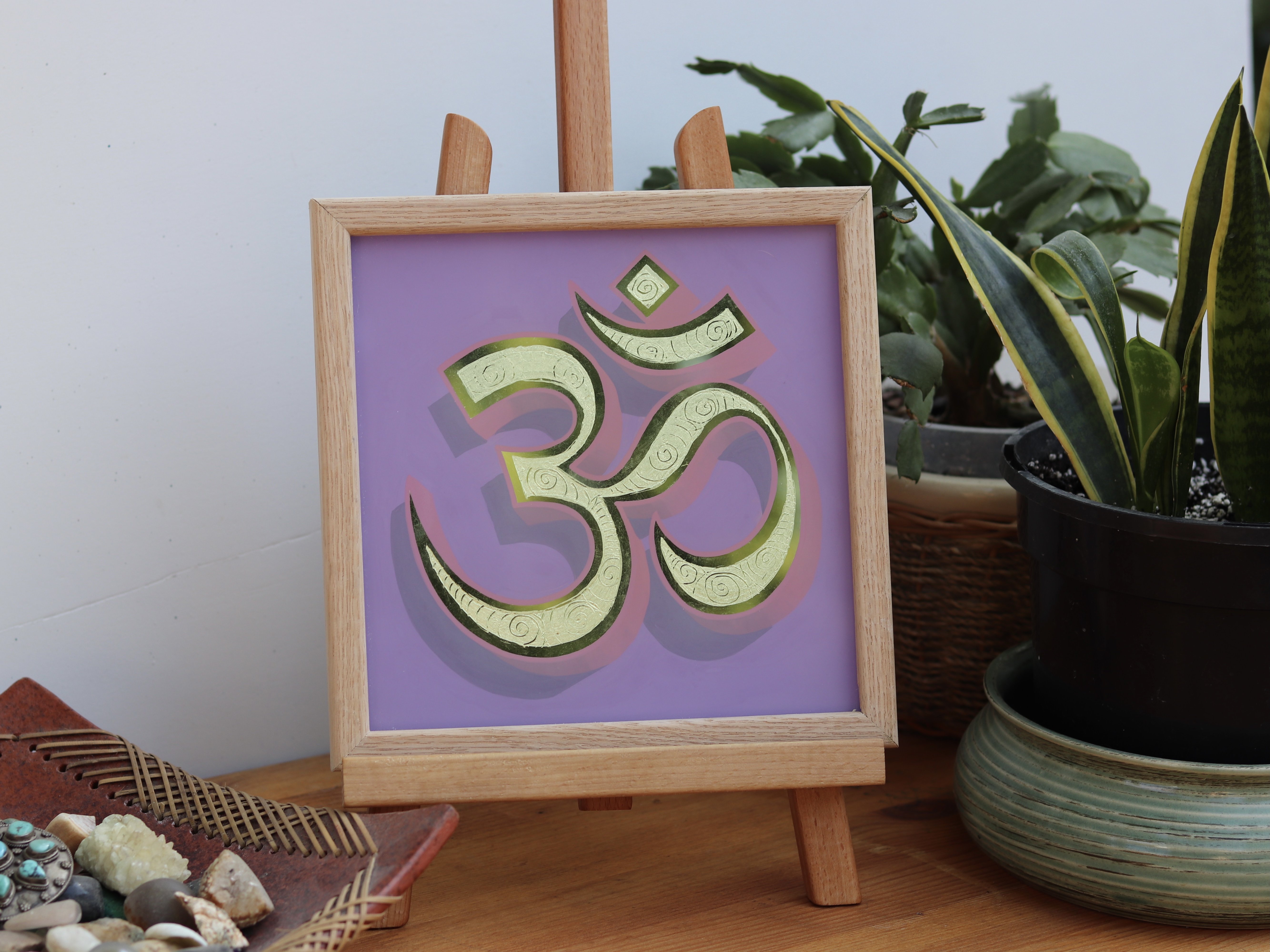 Oak framed reverse glass gold leaf Ohm symbol on a light violet background