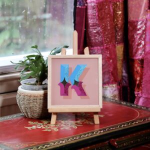 Reverse glass gilded circus style letter K in blues, violets, gold and glitter