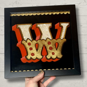 Stunning reverse glass gold leaf circus style letter W handcrafted in 23ct gold leaf, damar varnish technique & infilled with abalone shell and glitter and framed in a black wood frame