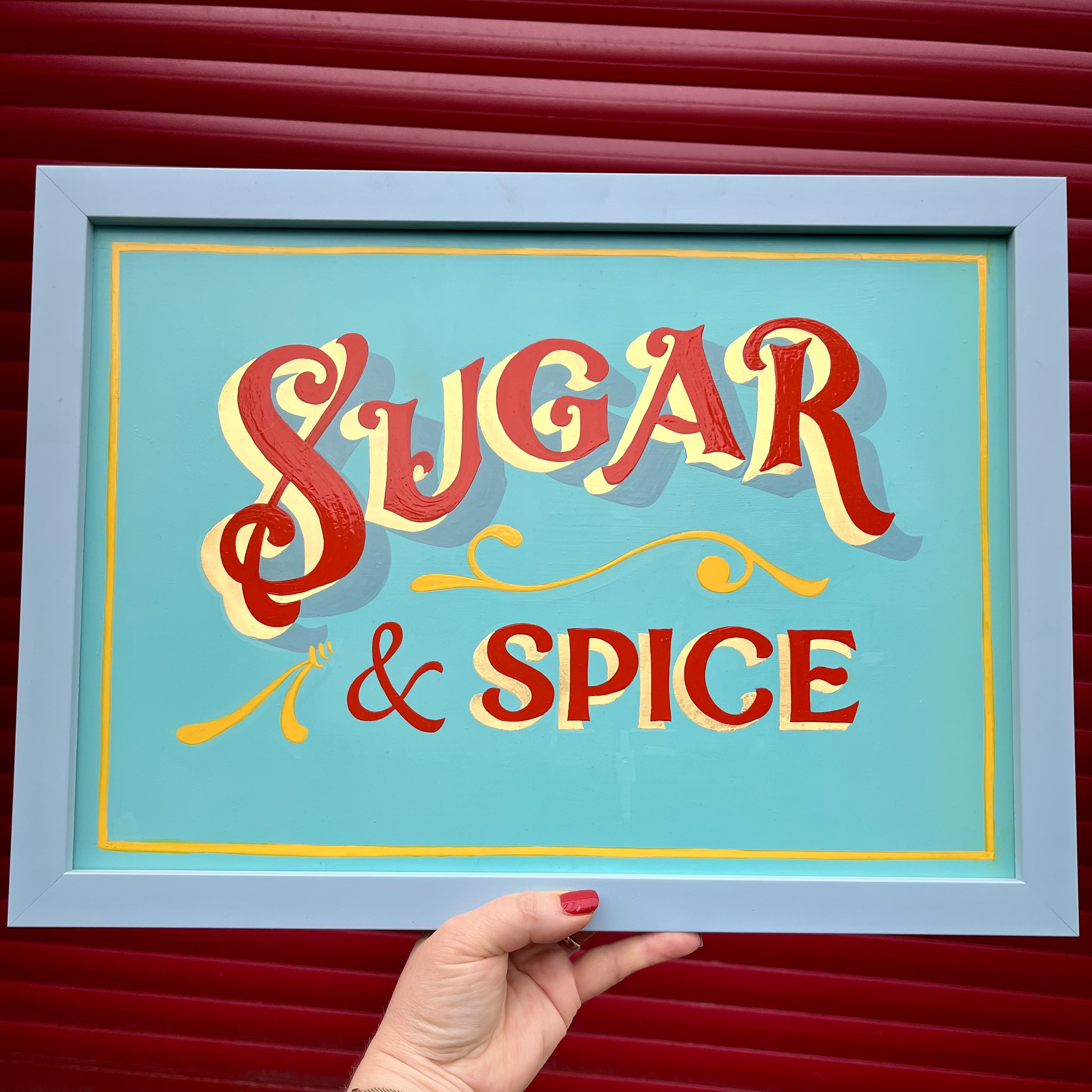 Handpainted and Gilded typography wall art sign in red & yellow enamel paints and 23ct gold leaf on a light blue background and framed in a blue wood frame