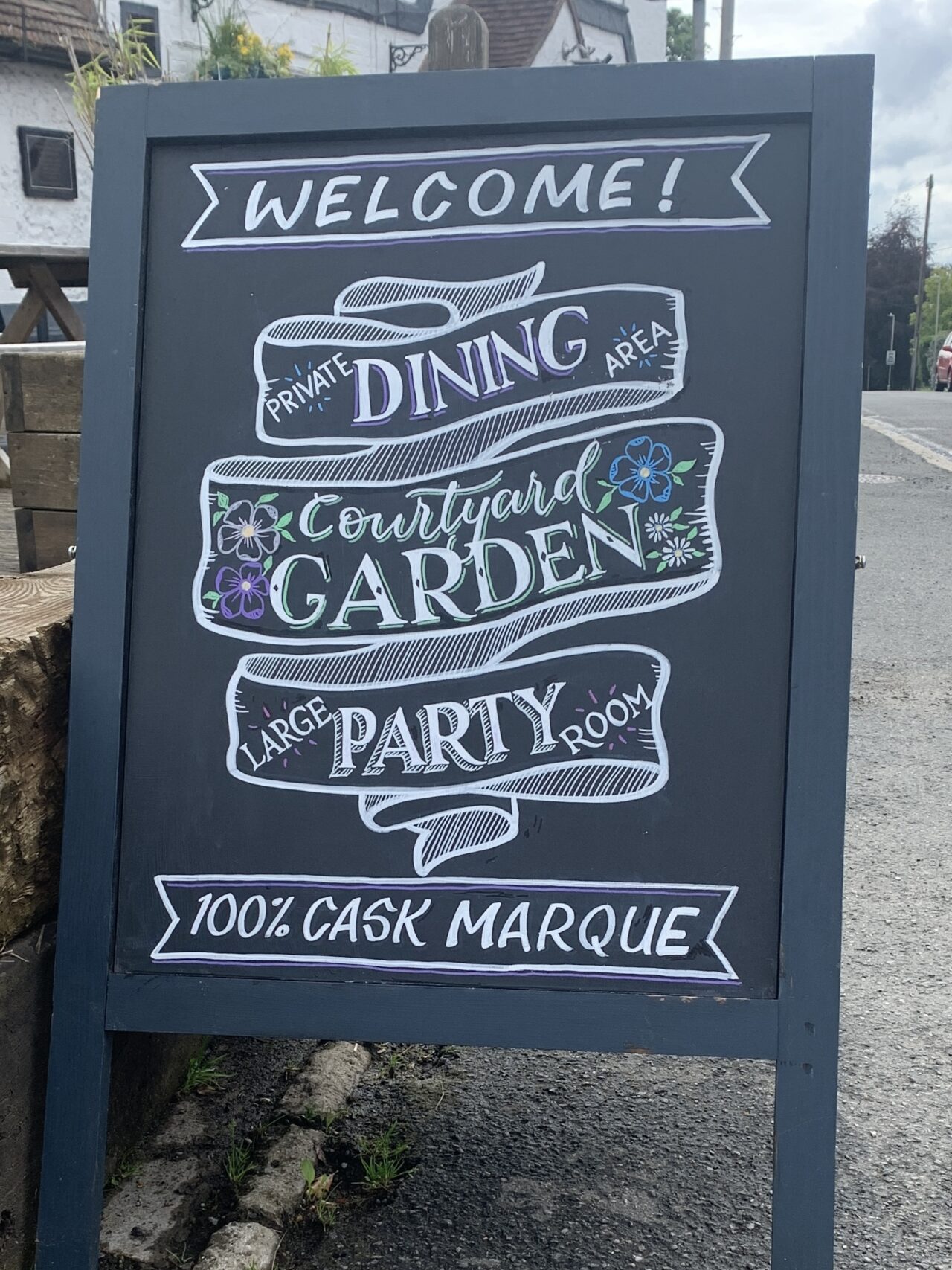 Blackboard WELCOME A-board chalk sign FEATURING A RIBBON FOLDED 3 TIMES WITH dINING gARDEN AND pARTY WRITTEN in white with floral details