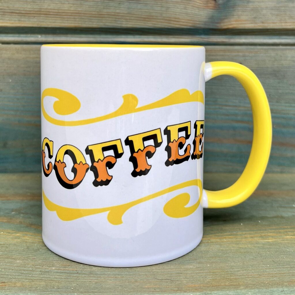 White & yellow ceramic mug with Circus Style hand-lettered ‘COFFEE’ design