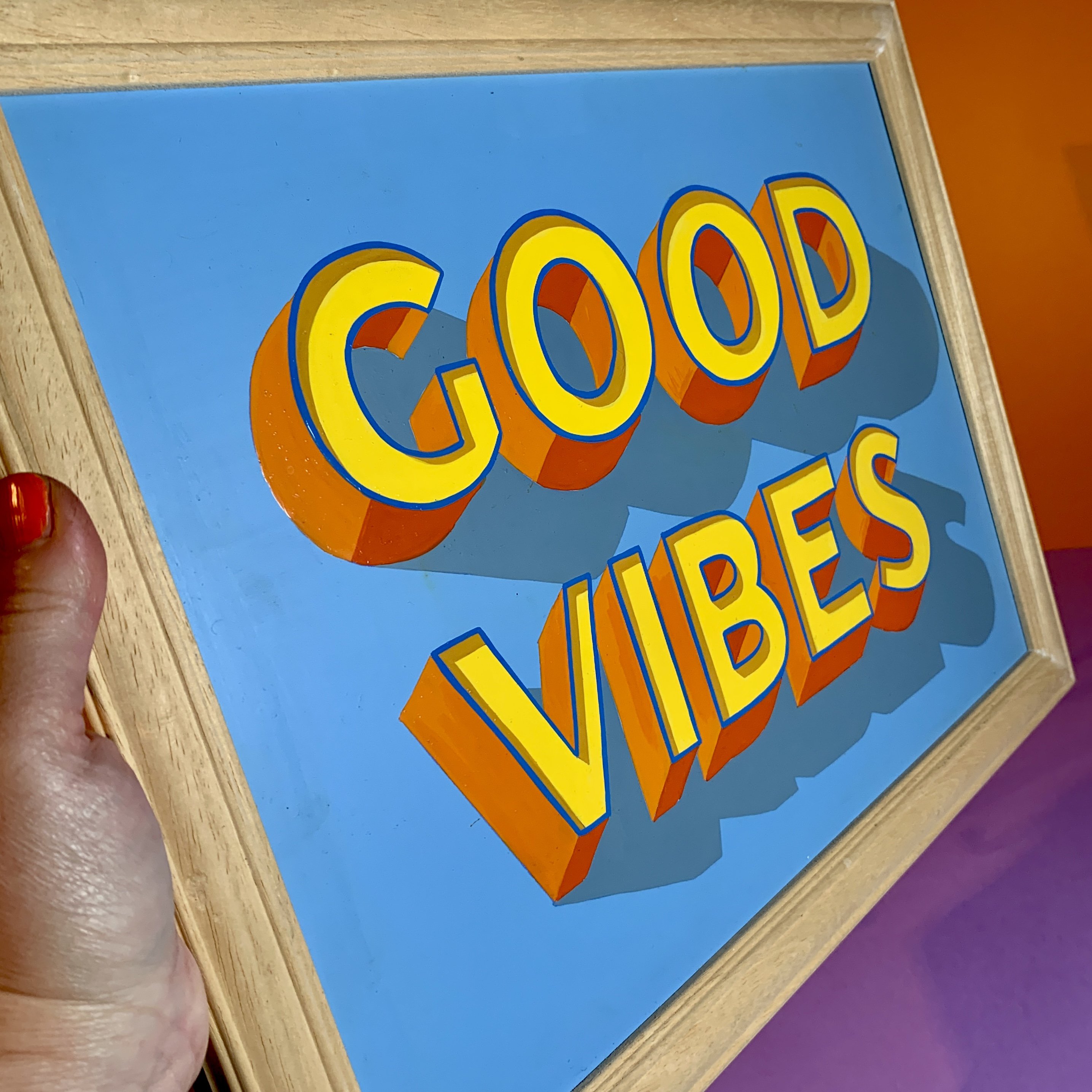 Hand-painted Sign Art GOOD VIBES in vibrant yellow and oranges on a light blue background and framed in real wood